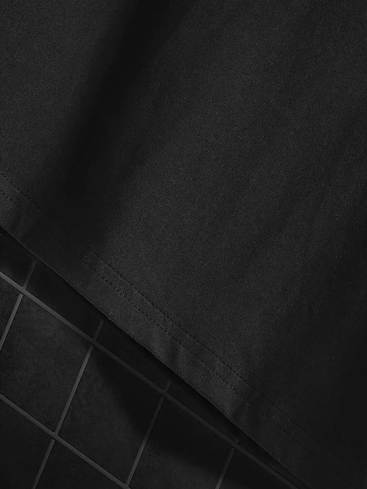 Men's black T-shirt fabric close-up with visible stitching and textured material.