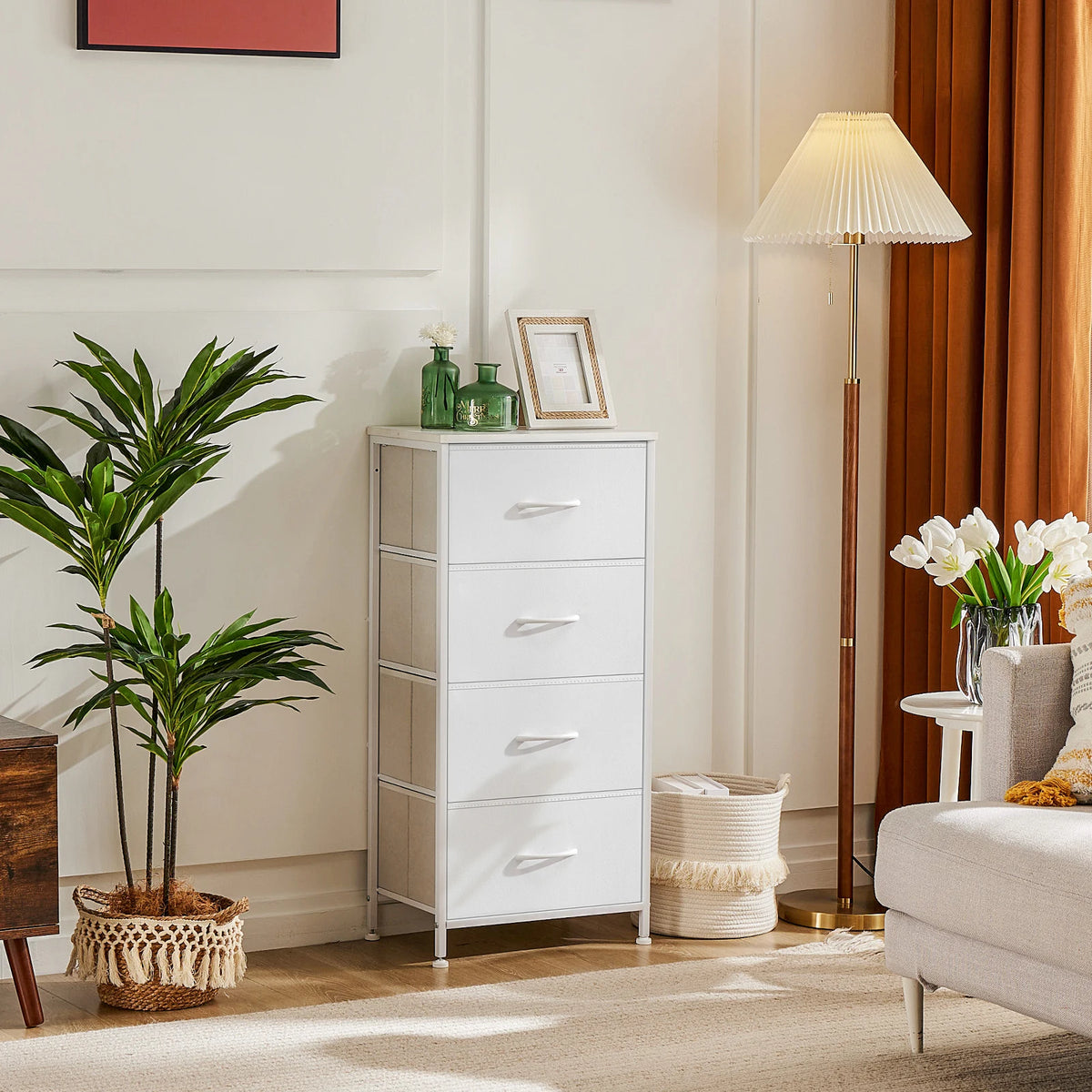 JHK 4-drawer fabric dresser on a steel frame in white, in a bright bedroom with plants and a lamp.