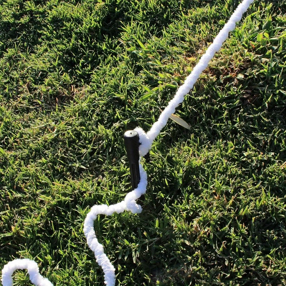 Giant Spider Web Outdoor Decor with white fuzzy rope stretched around a black stake in a grassy yard