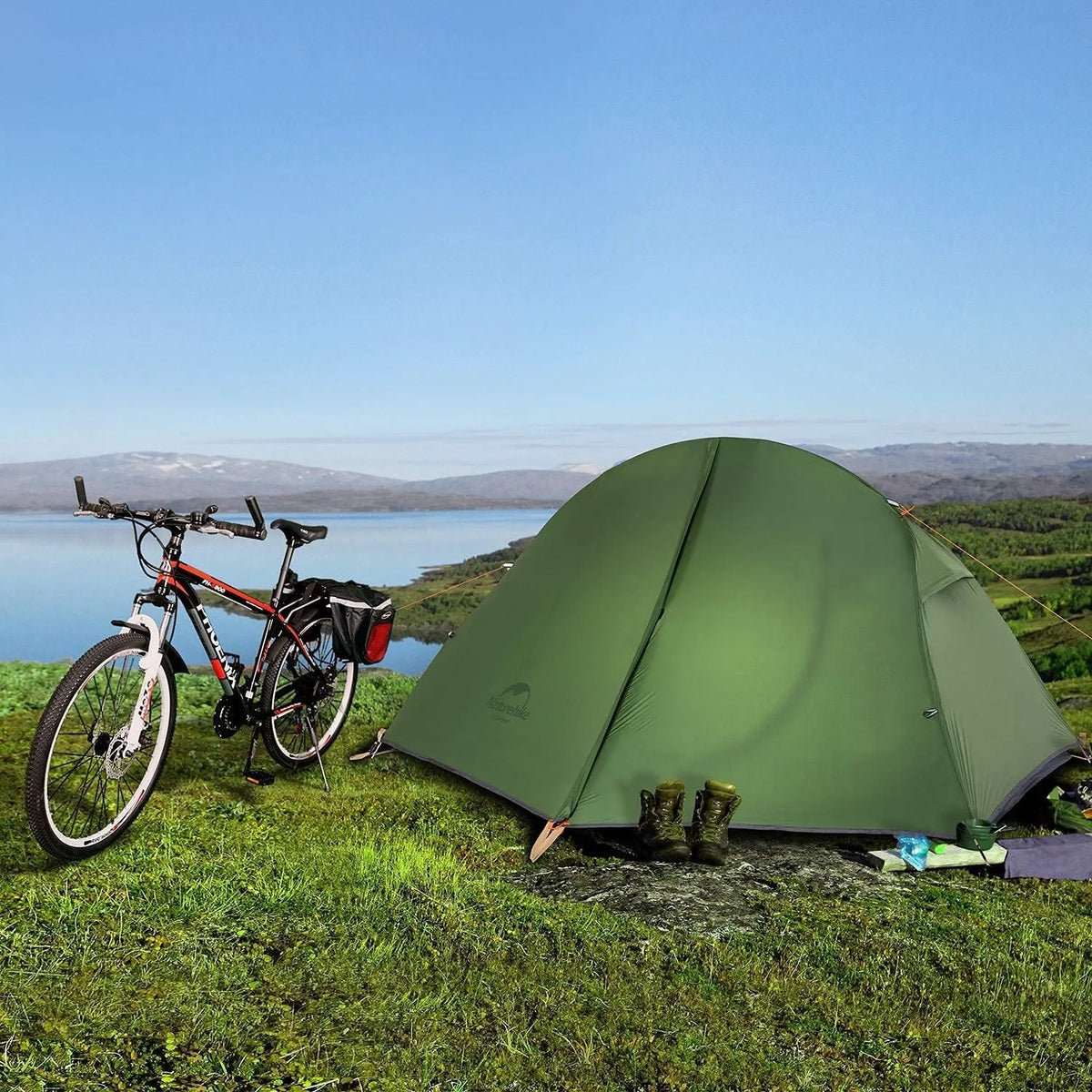 Naturehike 1-person camping tent in green, pitched beside a bicycle at a lakeside campsite.