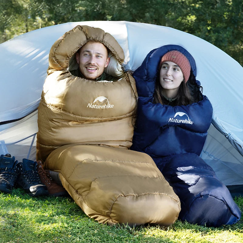 Naturehike mummy sleeping bags in brown and navy for two adults, camping outdoors beside a white tent