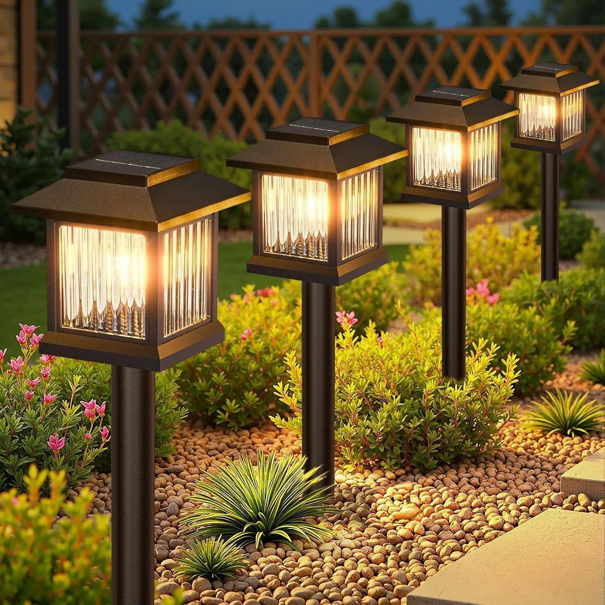 Solar pathway lights by S And B Enterprise; four bronze lanterns with glass panels along a pebble garden path.