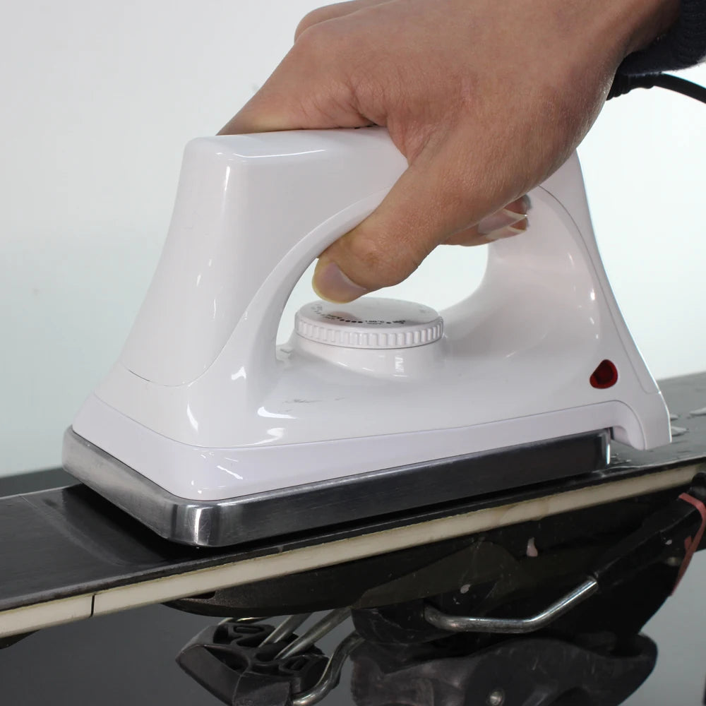 Ski and snowboard waxing iron with white body, adjustable temperature dial, red indicator light.
