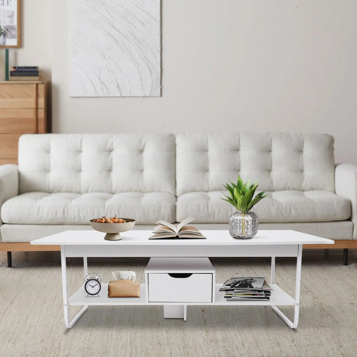 Modern white coffee table with two tiers and a drawer, beside a white sofa.