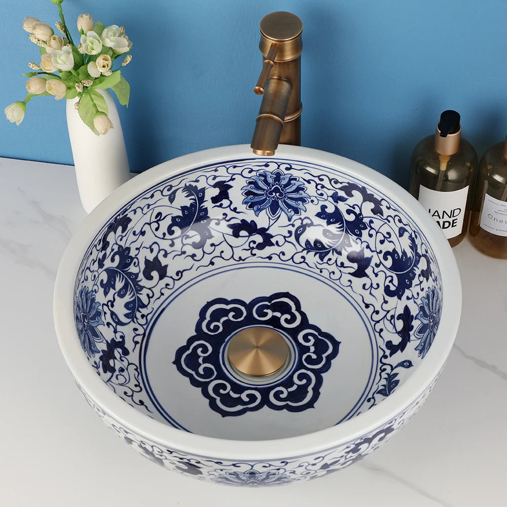 Round ceramic bathroom vessel sink with blue floral pattern and brass mixer faucet.