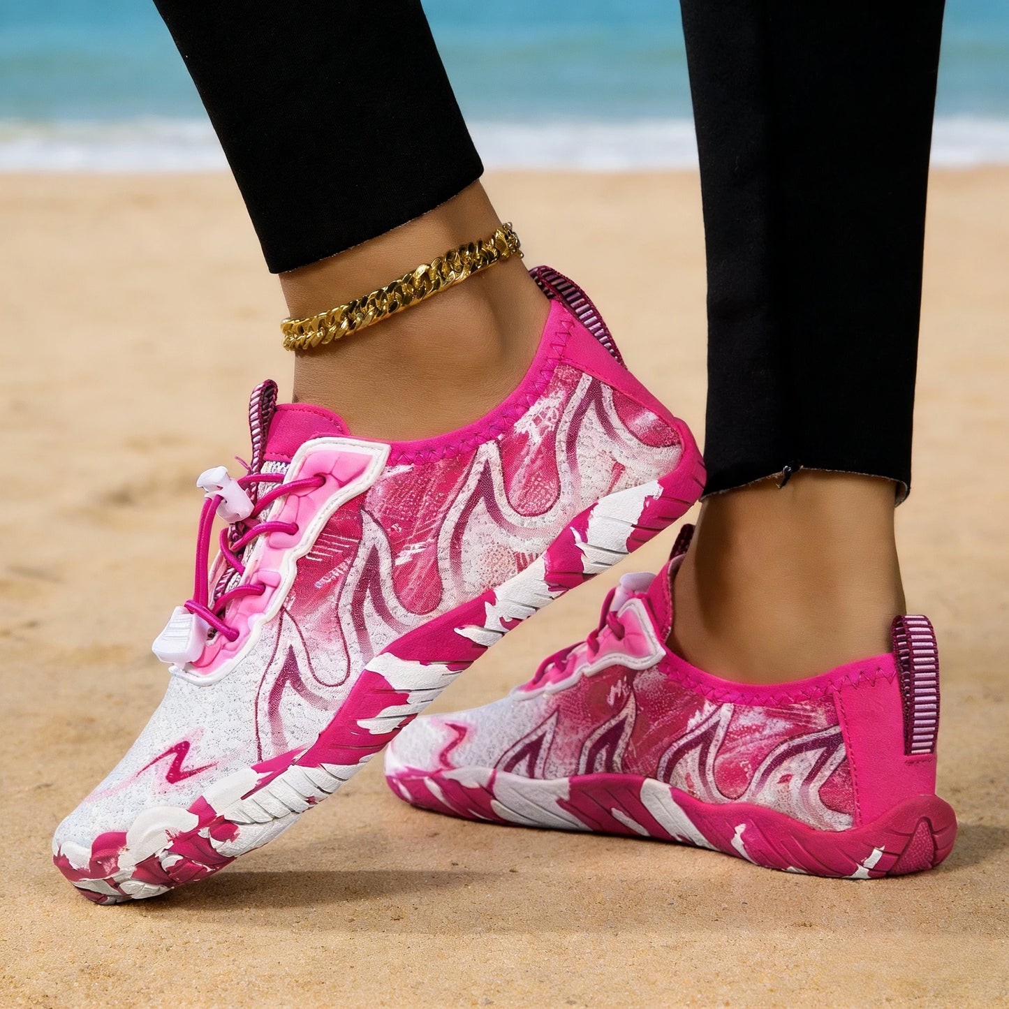 Women’s pink gradient water shoes on both feet at the beach; white soles.