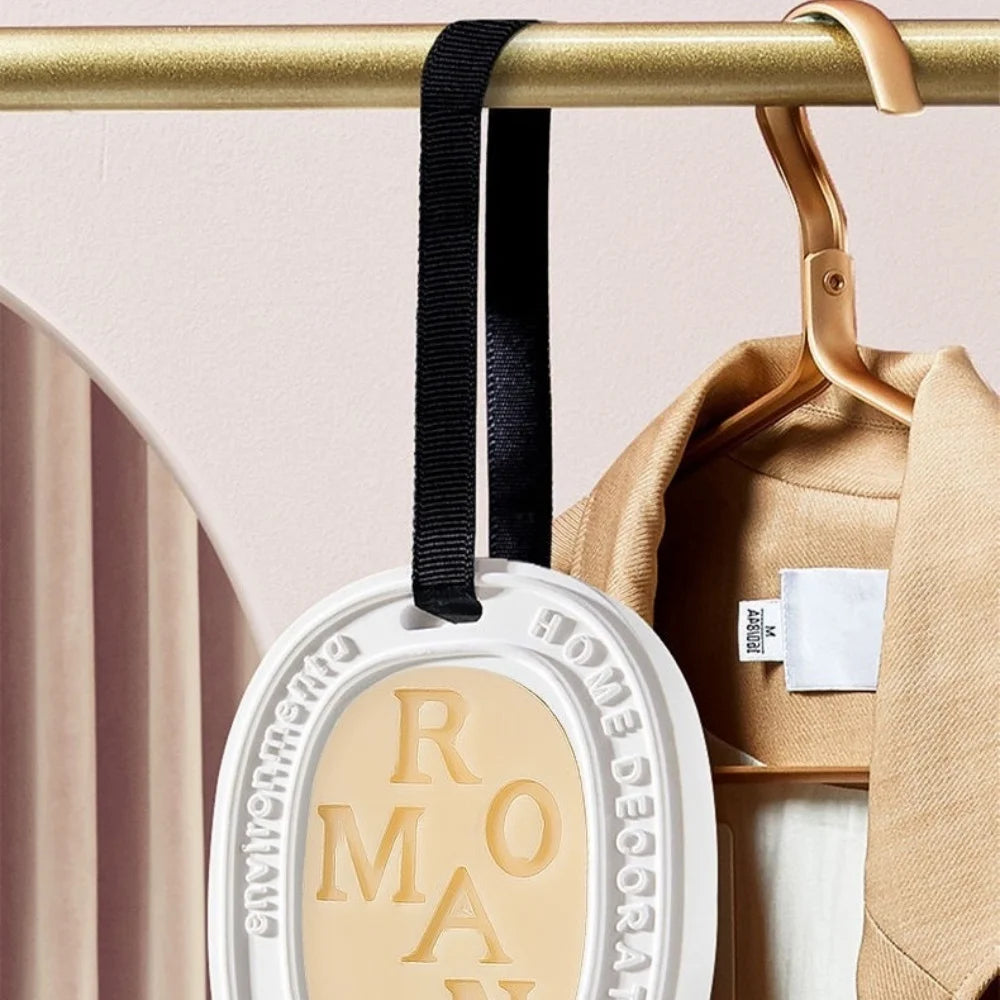 Hanging aromatherapy tablet pendant by S And B Enterprise, white circular design with beige center and black ribbon.