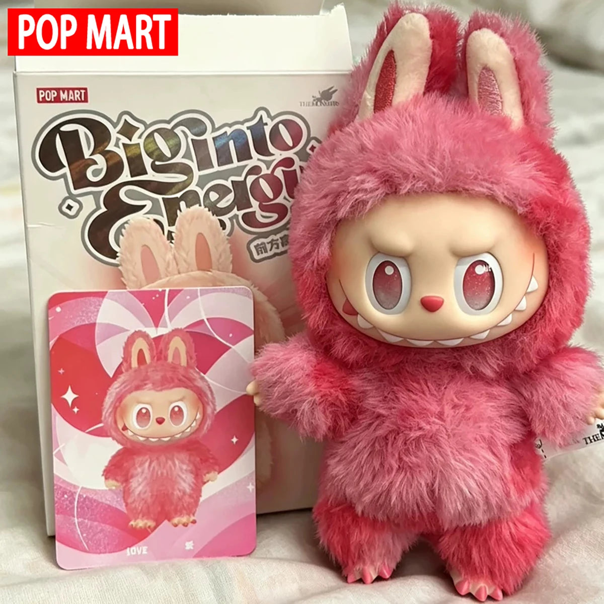 Labubu plush doll, pink macaron fur with bunny ears, beside POP MART box