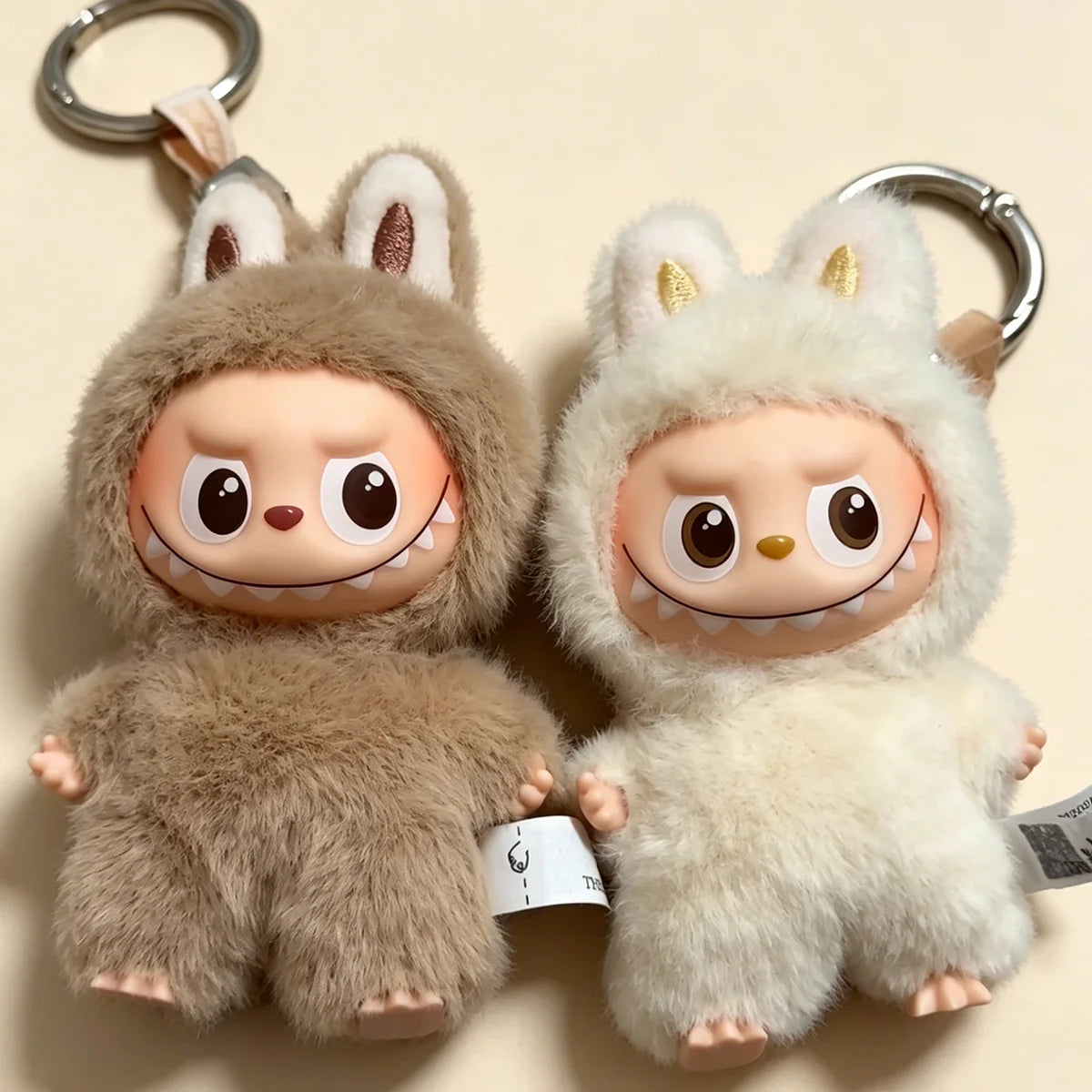 Labubu plush dolls keychains, two brown and white furry creatures with bunny ears, big cartoon eyes, soft fur