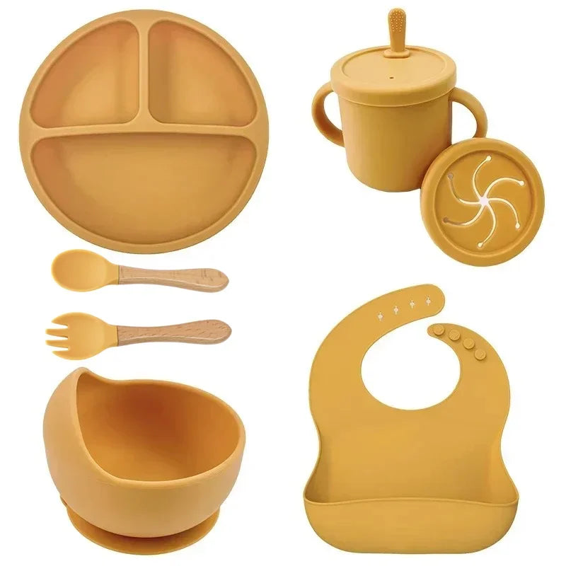 7-piece mustard-yellow silicone baby feeding set: divided plate, suction bowl, straw cup with lid, spoon, fork, bib