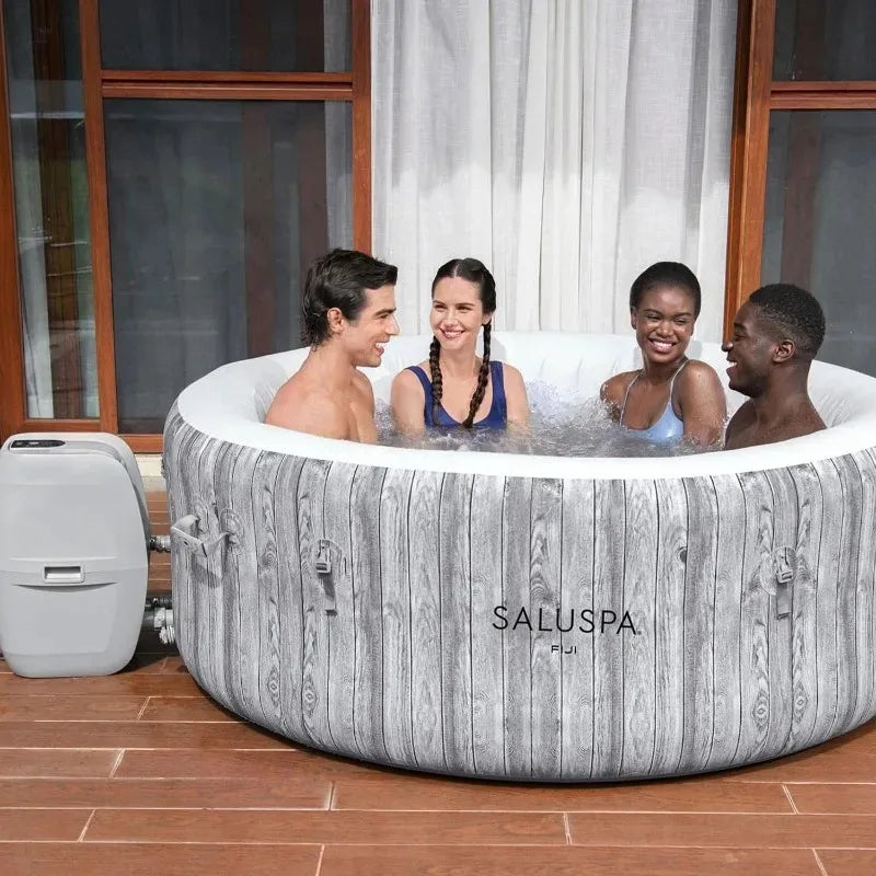 SaluSpa Fiji round inflatable hot tub with wood-grain exterior on a wooden deck, seating 4 people.