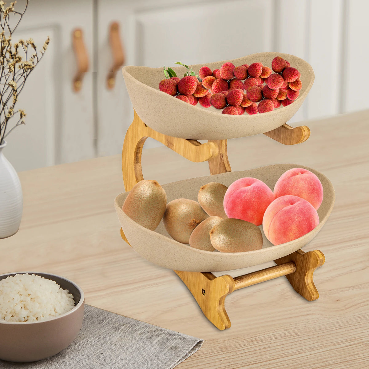 Two-tier fruit stand with beige stoneware bowls on a wooden rack, filled with lychees, kiwis and peaches.