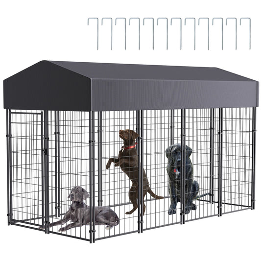 Large outdoor dog kennel with welded wire panels and dark canopy; includes ground stakes and several dogs inside.