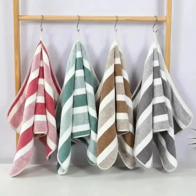 4-piece striped bath towel set in pink, teal, brown and gray hues, hanging on a wooden rack; plush cotton blend.