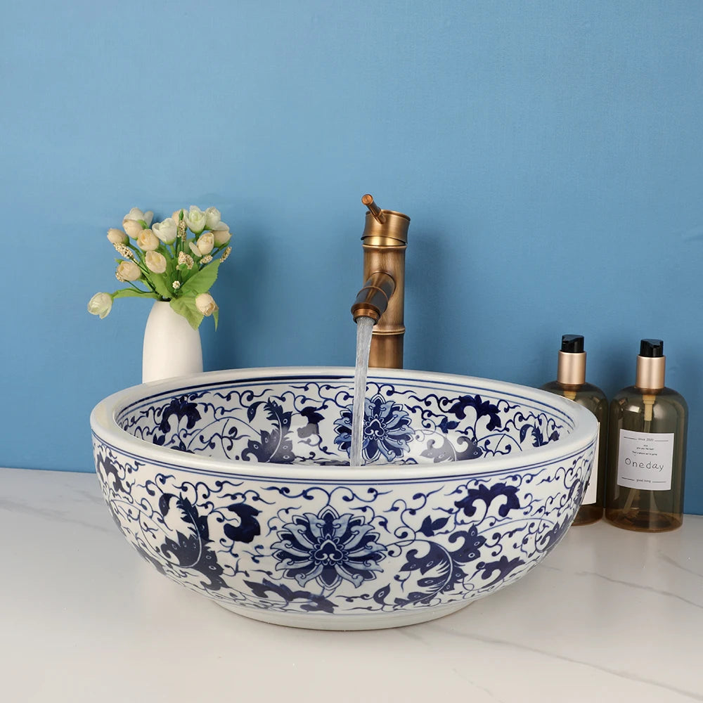 Blue-and-white ceramic bathroom vessel sink with bronze faucet on a marble countertop.