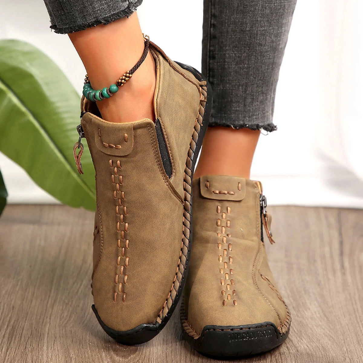 Pair of tan suede ankle boots with braided side trim and stitched detailing.