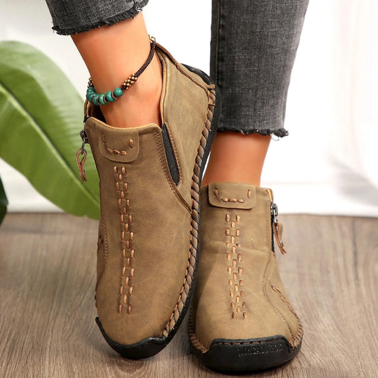 Pair of tan suede ankle boots with braided side trim and stitched detailing.