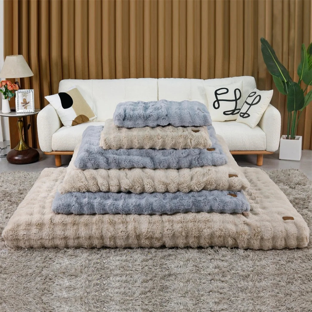 Ultra plush dog bed, large beige base with blue-gray and beige faux fur cushions on a living room rug.