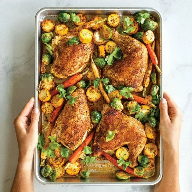 Aluminum half-sheet pan 18x13 by S And B Enterprise with four bone-in chicken pieces and roasted vegetables