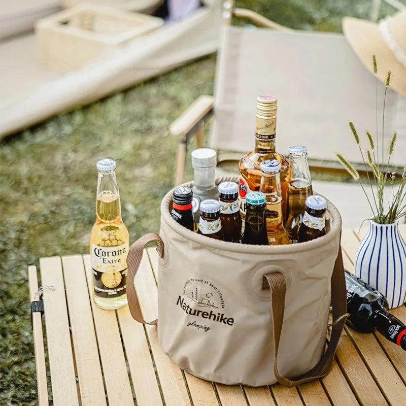 Naturehike handheld foldable beige bucket with brown handles, filled with several beverage bottles for camping.