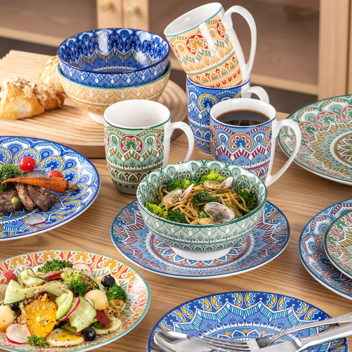 Porcelain dinnerware set with Bohemian mandala patterns; includes plates, bowls and mugs in blue, green and orange