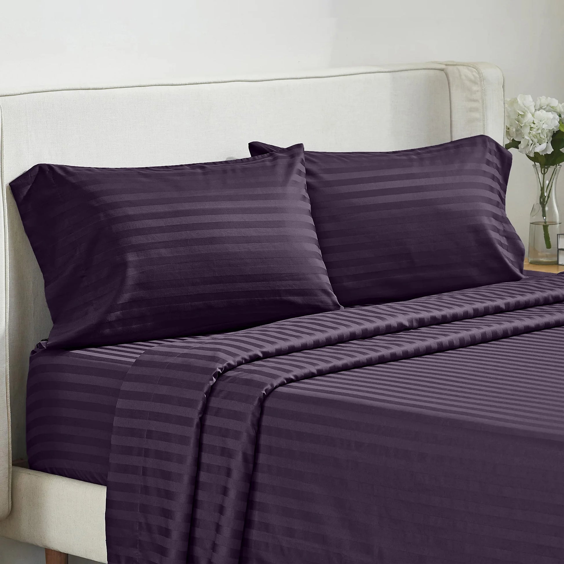 Battilo 4-piece purple striped bed sheet set with pillowcases on a beige upholstered bed