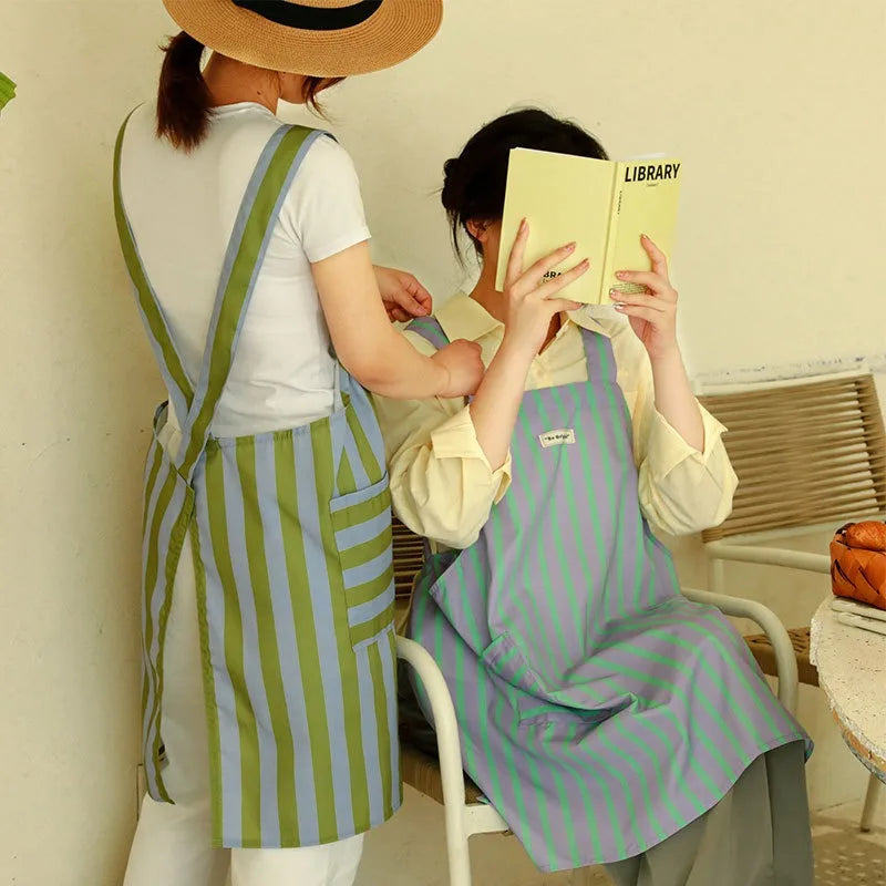 S And B cross-back striped kitchen apron with pocket, blue-green, worn by two women.
