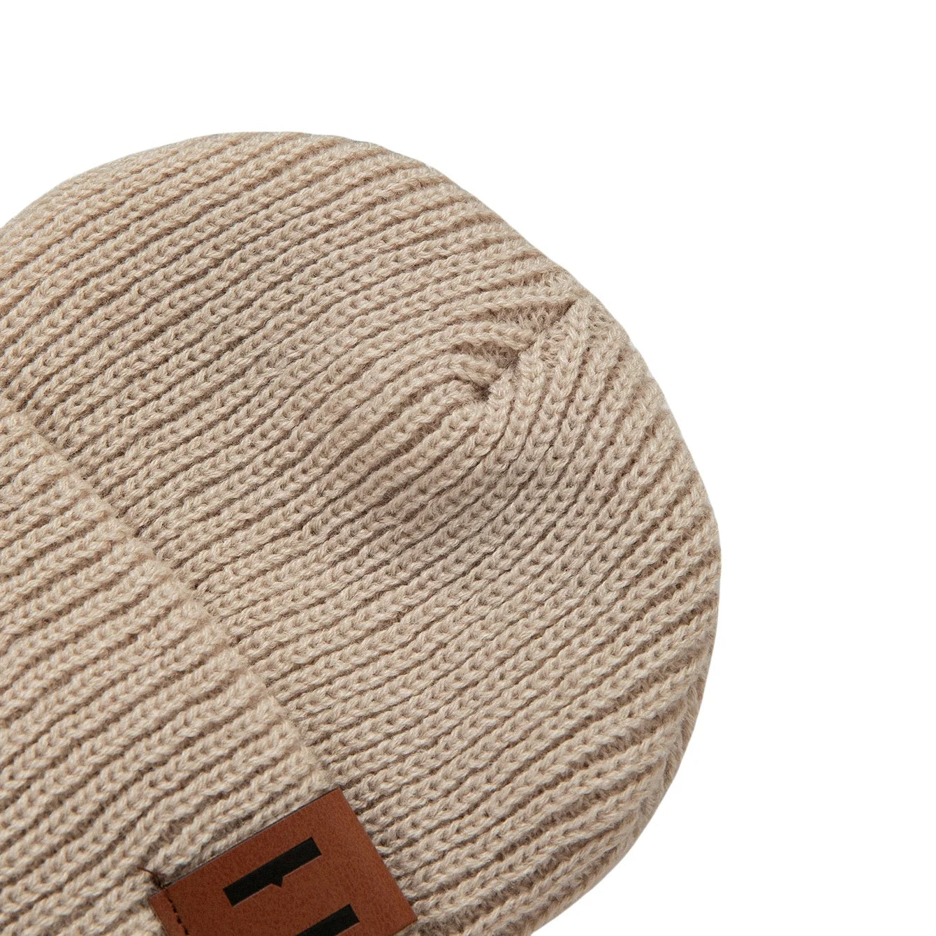 Beige knitted baby beanie hat with brand tag by S And B Enterprise.