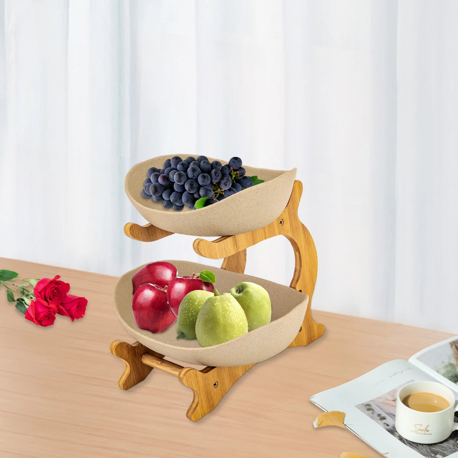 Two-tier fruit stand with beige bowls on a natural wood frame, grapes on top and apples/pears on bottom