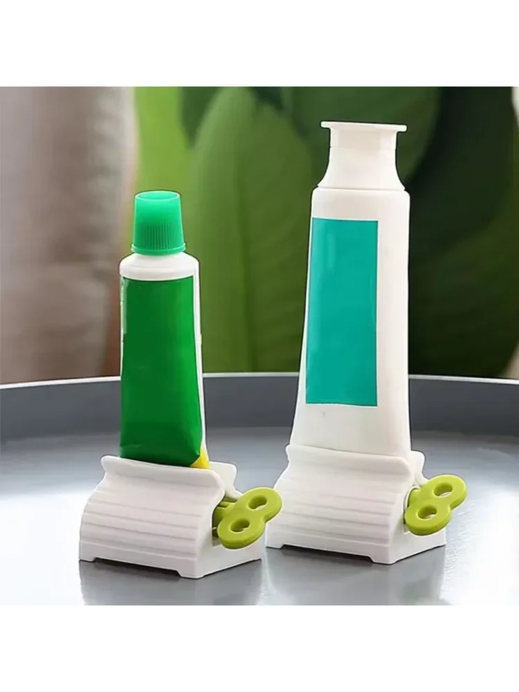 Two toothpaste tube squeezers by S And B Enterprise; white bases with green wheels and green and teal labels.