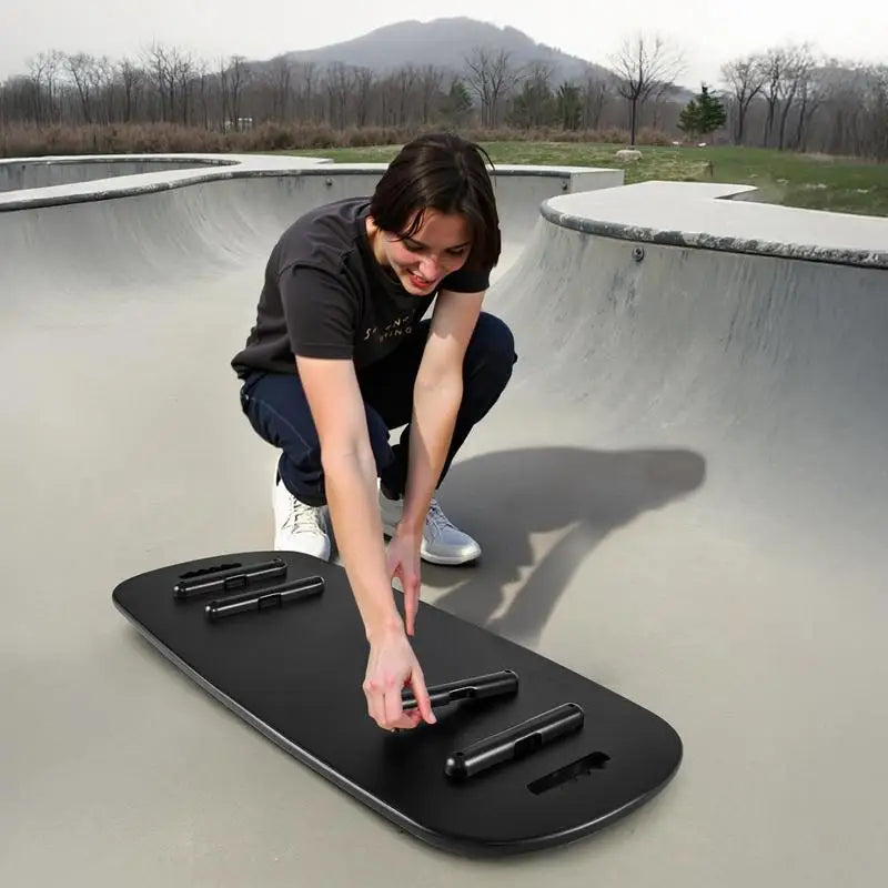 Balance board trainer, black wobble board with built-in rollers, outdoors at a skate bowl