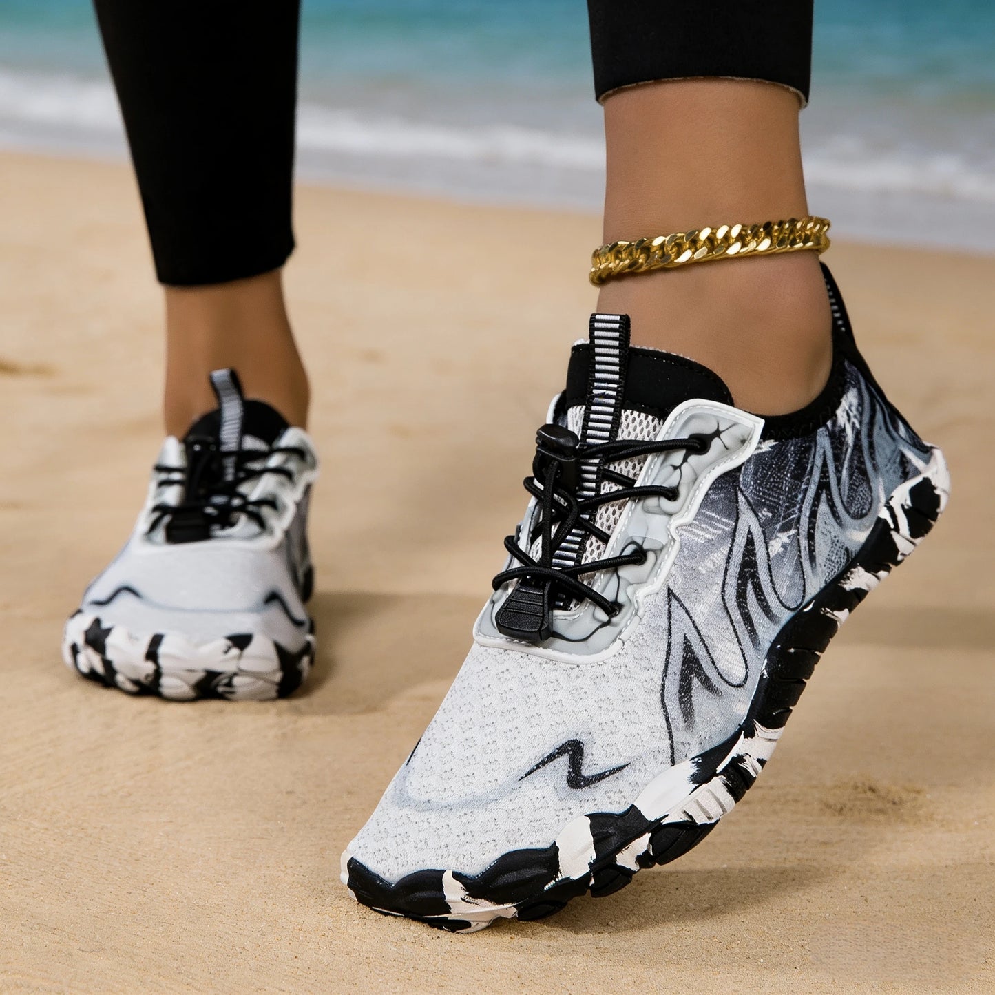 Women water shoes with gray camo pattern, pair on sandy beach
