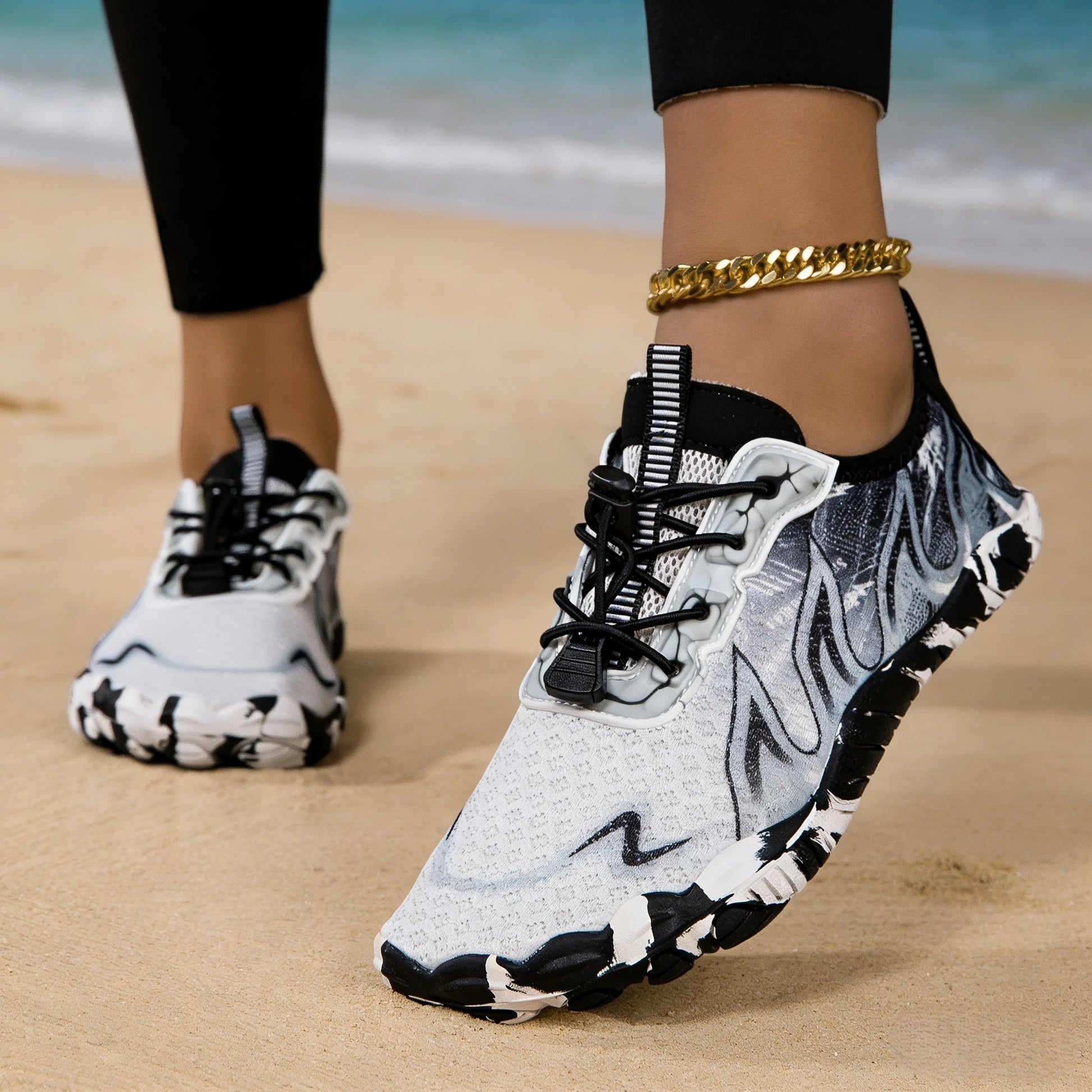 Women water shoes with gray camo pattern, pair on sandy beach