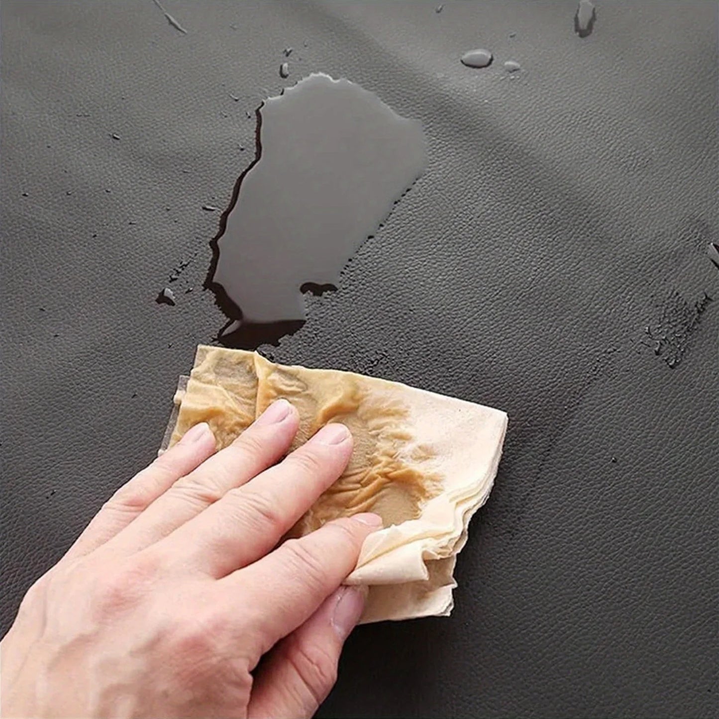 PU leather heavy-duty waterproof apron being wiped with a cloth on a dark textured surface