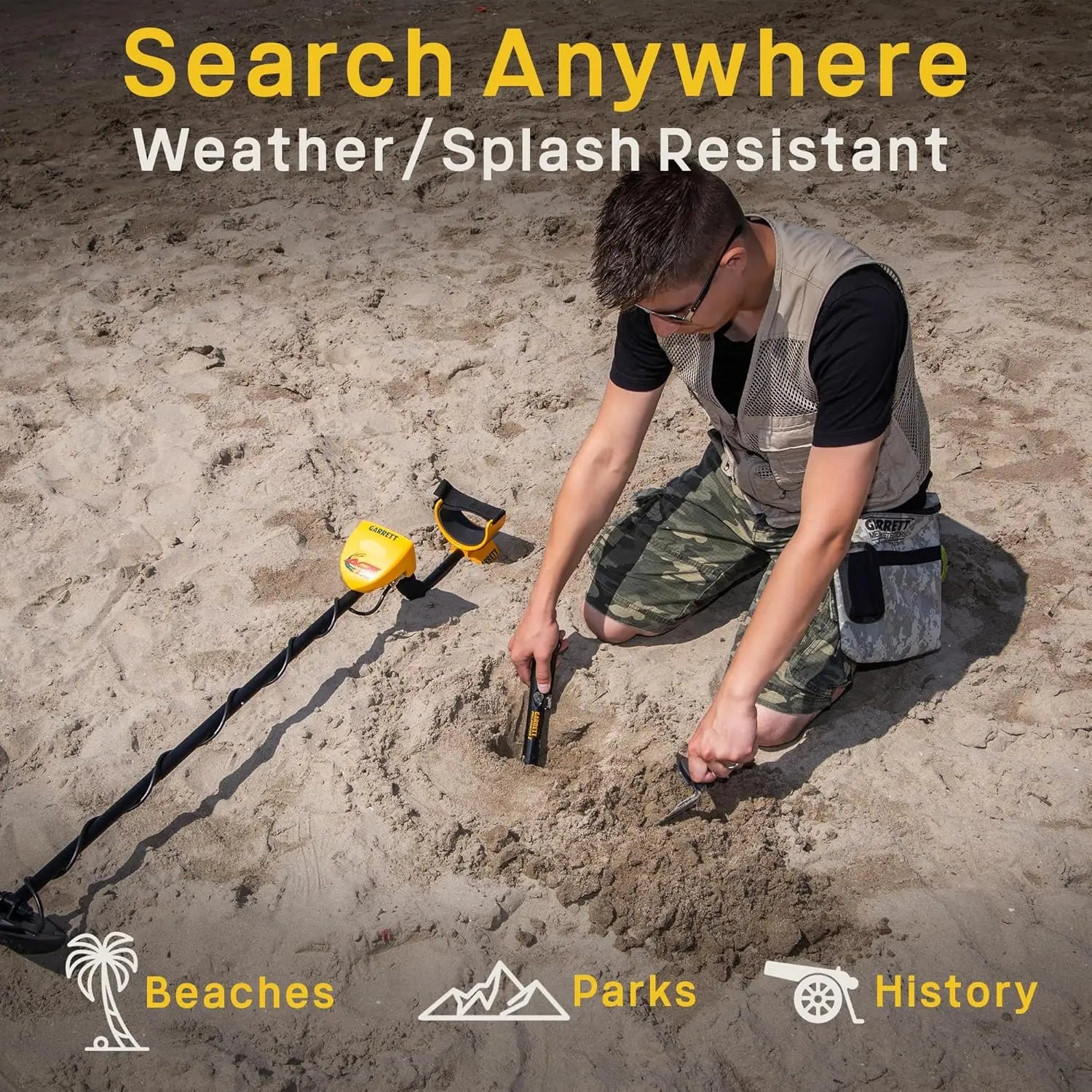 Garrett metal detector for adult treasure hunting on a sandy beach; yellow search coil and user in camo shorts.