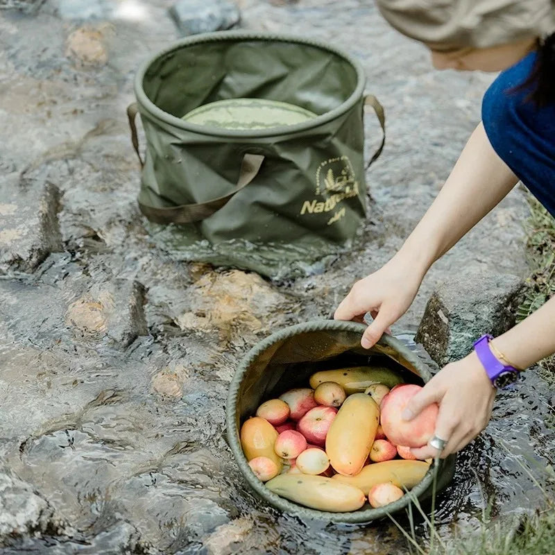 Two Naturehike foldable green handheld buckets with brown handles; waterproof, one filled with apples and pears.