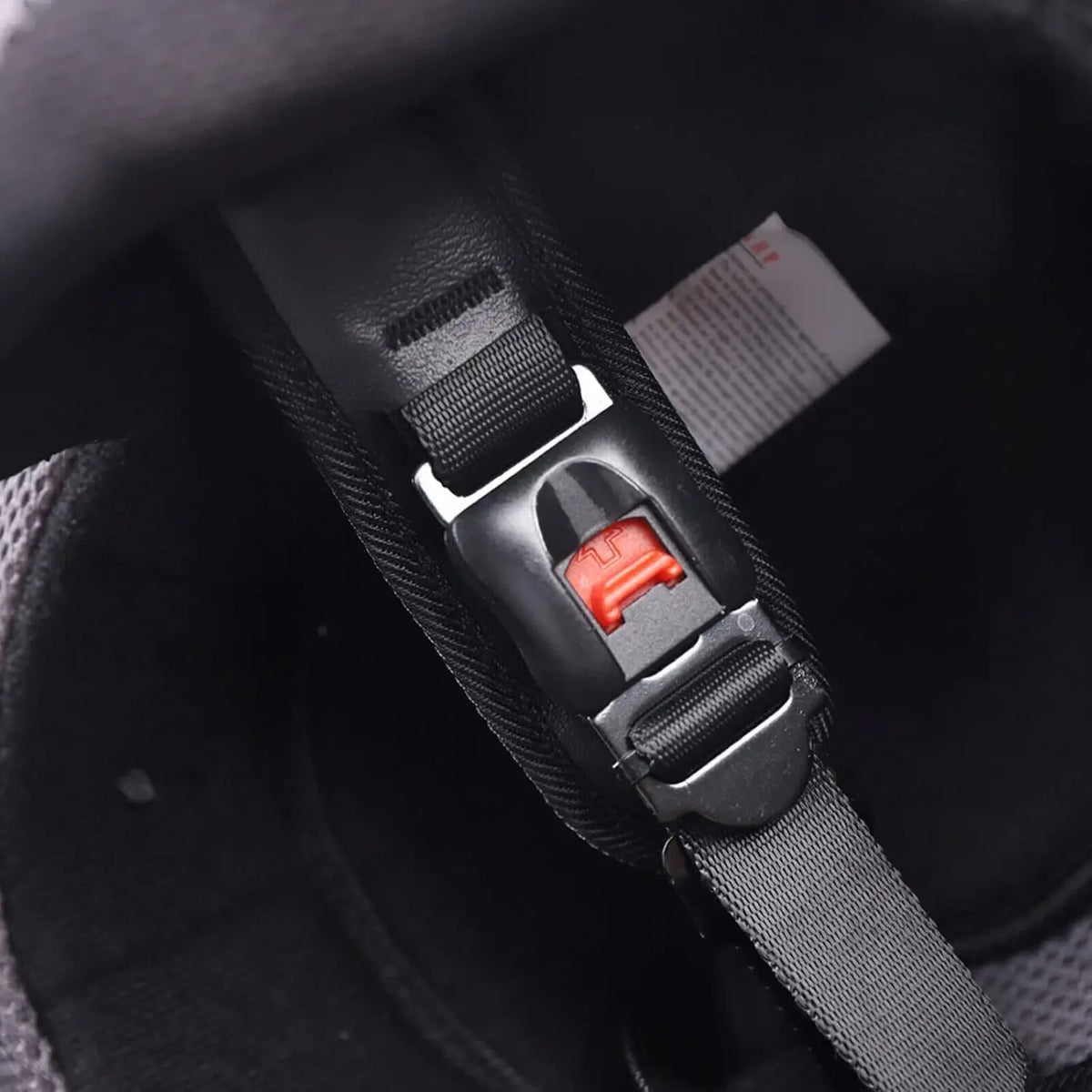 Motorcycle full-face helmet interior chin strap with red quick-release buckle on black webbing