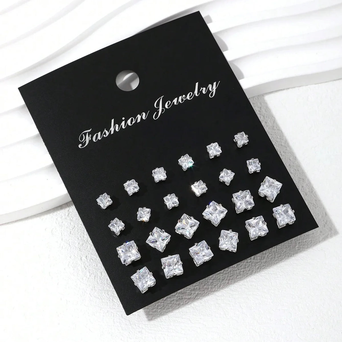 Square-cut cubic zirconia stud earrings, 12 pairs on a black fashion jewelry display card.