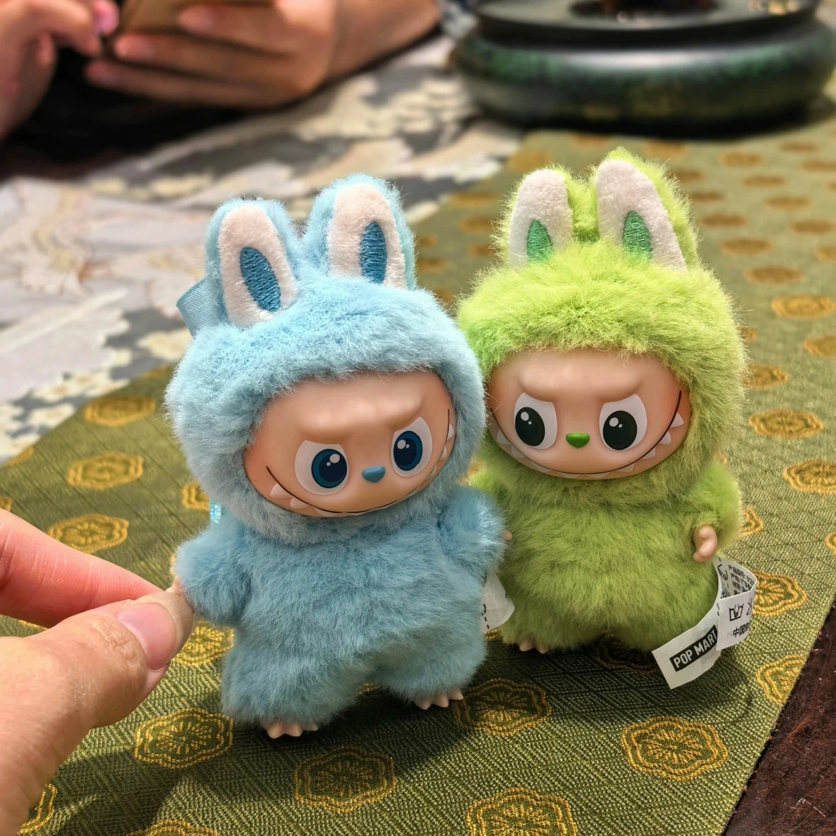 Labubu plush dolls, blue and lime-green fuzzy outfits with bunny ears; 2 figures.
